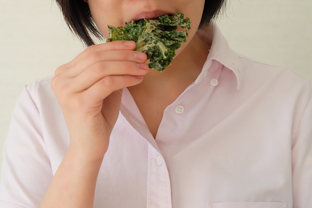 Woman eating a kale chip that contains vitamin K1.