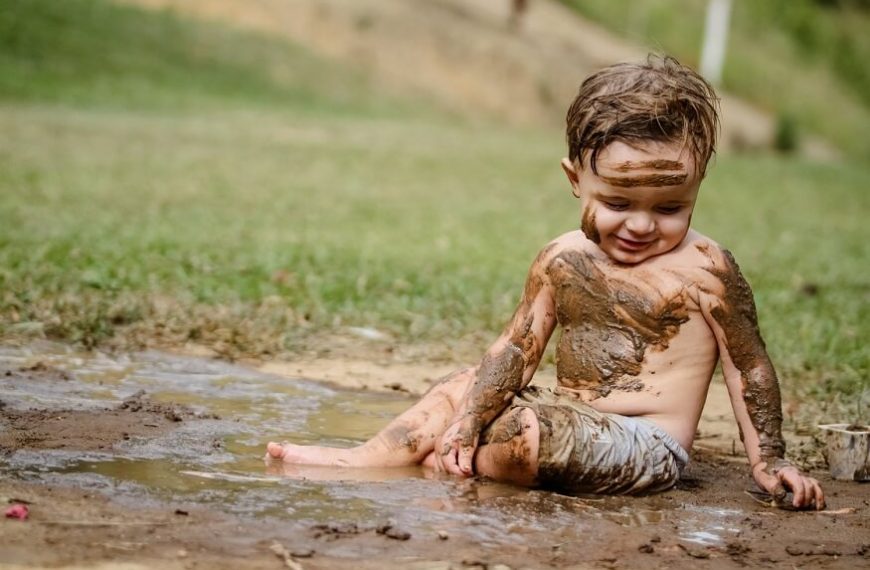 Little boy playing in mud.