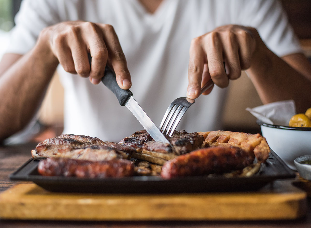 Man eating a lot of cooked meats.