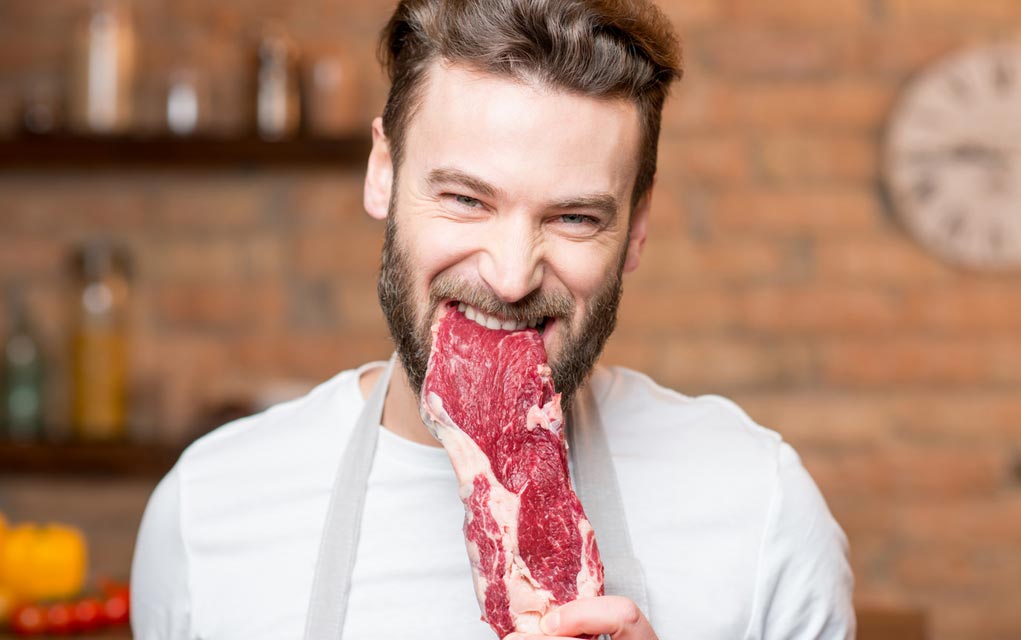 Man eating a raw steak.